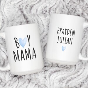 Puede incluir: Dos tazas de cer&aacute;mica blanca con texto negro y corazones azules. Una taza dice "Boy Mama" y la otra dice "Brayden Julian".