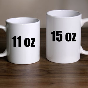 Puede incluir: Dos tazas de cer&aacute;mica blanca con texto negro. La taza m&aacute;s peque&ntilde;a es de 11 oz y la taza m&aacute;s grande es de 15 oz.