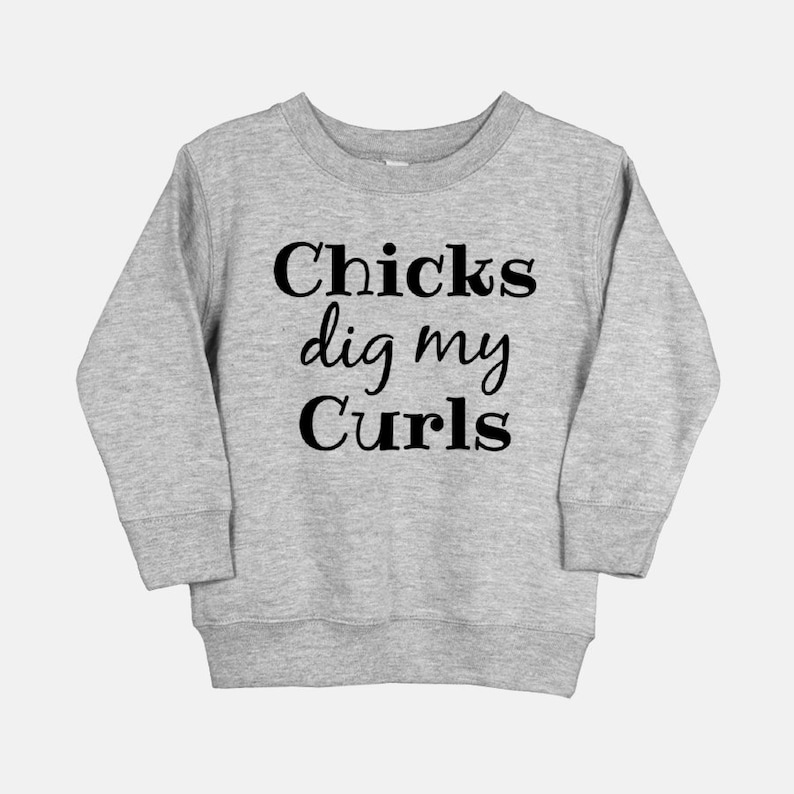 Puede incluir: Una sudadera gris con el texto "Chicks dig my Curls" impreso en negro.