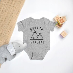 May include: A gray baby onesie with a black mountain graphic and the text "Born to Explore".