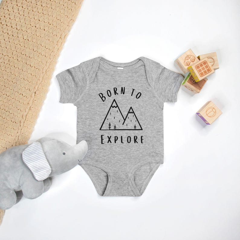 May include: A gray baby onesie with a black mountain graphic and the text "Born to Explore".