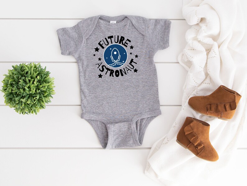 May include: Gray baby bodysuit with a blue and black rocket graphic and the text "Future Astronaut" in a circle.