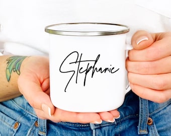 May include: White enamel mug with a black cursive inscription that reads "Stephanie".