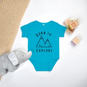 May include: A turquoise baby onesie with a black mountain graphic and the text "Born to Explore".