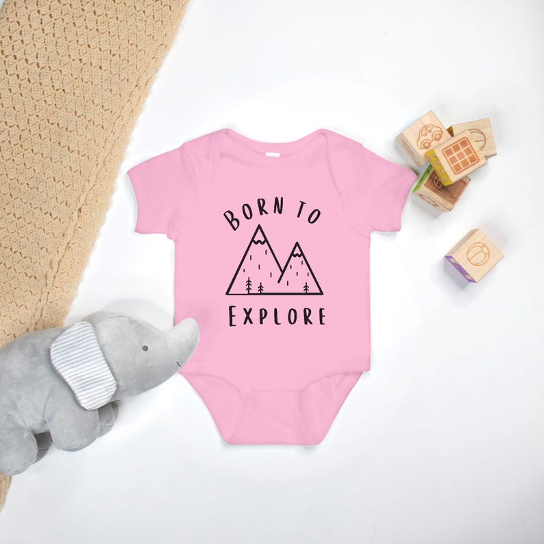 May include: Pink baby onesie with a black mountain graphic and the text "Born to Explore".
