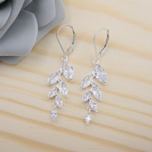 May include: A pair of silver dangle earrings with clear crystal stones in a leaf design.