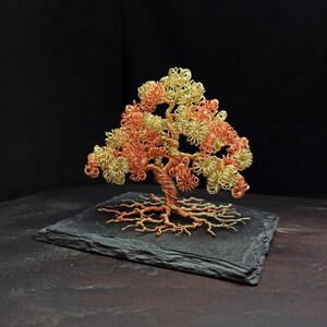 May include: A wire tree sculpture with a copper and gold finish. The tree is on a black slate base.