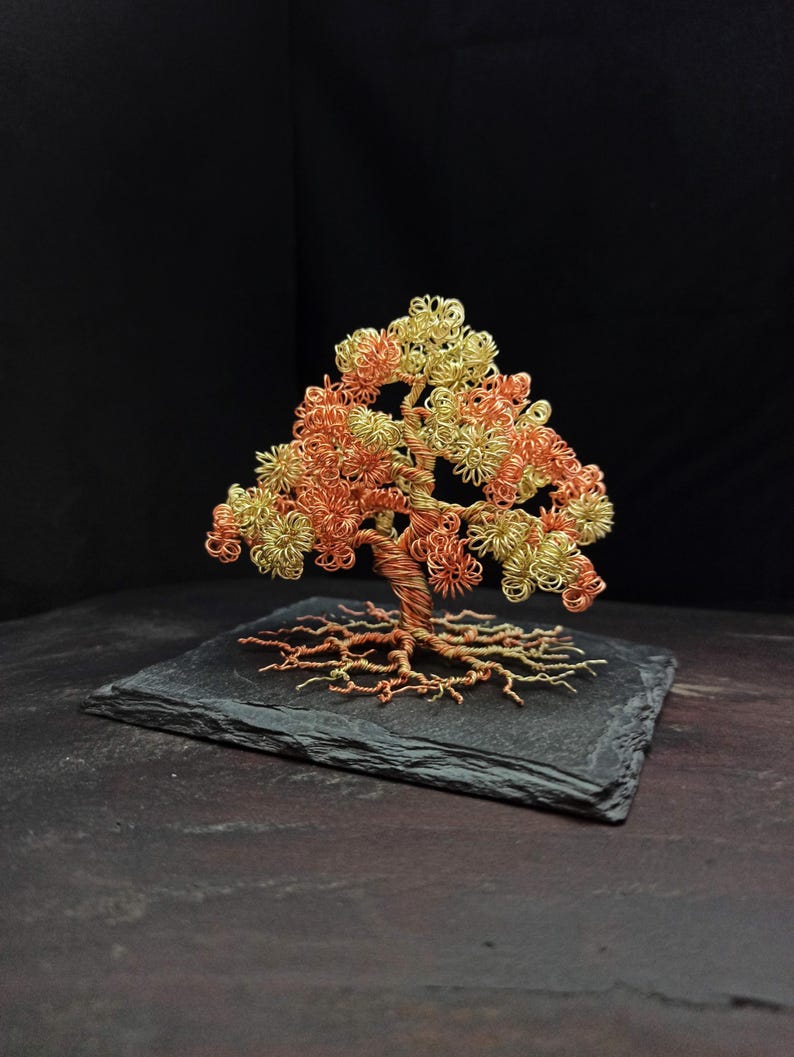 May include: A wire tree sculpture with a copper and gold finish. The tree is on a black slate base.