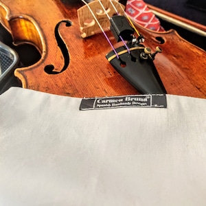 Könnte beinhalten: Nahaufnahme einer braunen Geige mit einem weißen Etikett, auf dem "Carmen Bruna Spanish Handmade Designs" steht.