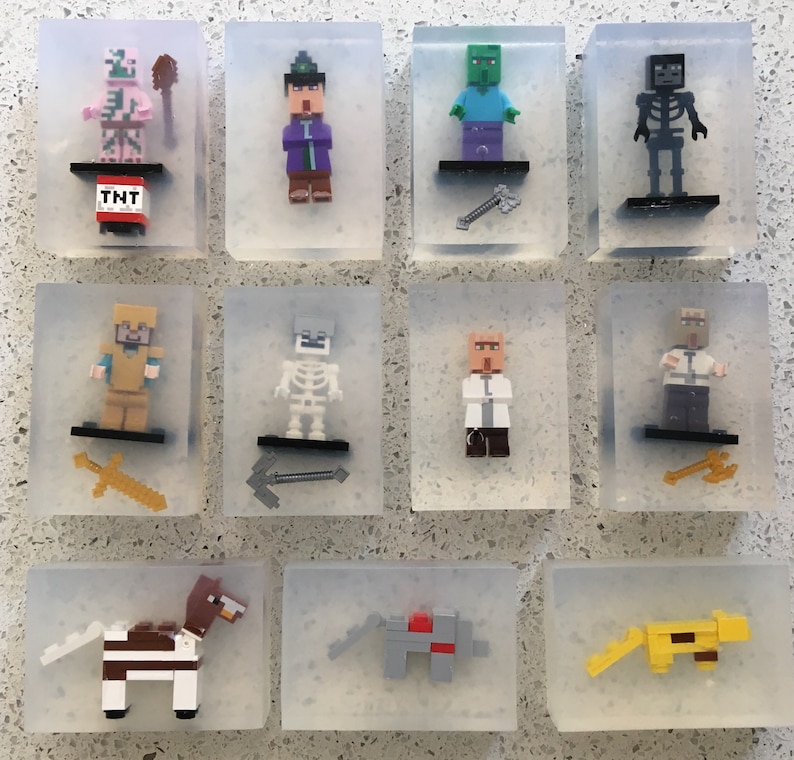 May include: Twelve clear plastic boxes each containing a different Minecraft character figurine. The characters include a pig, a wizard, a zombie, a skeleton, a knight, a skeleton, a scientist, a villager, a horse, a wolf, and a cat.