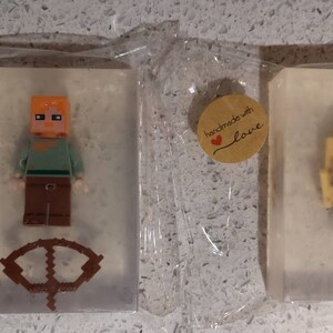 May include: Three clear soap bars with handmade with love labels. Each bar features a different Minecraft character: a figure with orange hair, a figure with brown hair, and a figure with yellow hair.