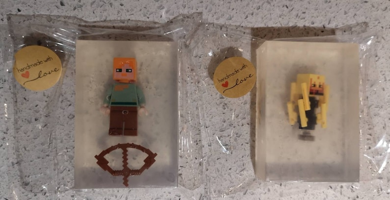 May include: Three clear soap bars with handmade with love labels. Each bar features a different Minecraft character: a figure with orange hair, a figure with brown hair, and a figure with yellow hair.