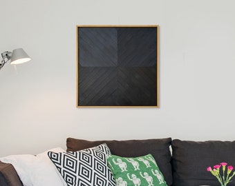 May include: A black and white geometric abstract art print in a wooden frame hangs on a white wall above a brown couch with pillows.