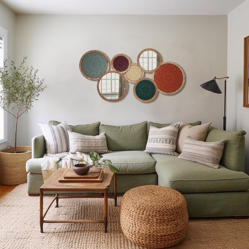 Peut inclure: Un salon avec un canap&eacute; vert sauge et des coussins &agrave; motifs. Au-dessus du canap&eacute;, une collection de miroirs ronds avec des cadres d&eacute;coratifs et des inserts &agrave; motifs color&eacute;s est accroch&eacute;e au mur. Un pouf en osier et une table basse en bois compl&egrave;tent l'espace.