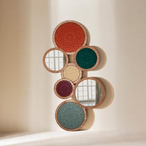 Peut inclure: Un ensemble de miroirs ronds avec des cadres en bois et des centres d&eacute;coratifs &agrave; motifs de diff&eacute;rentes couleurs, dont le rouge, le vert et le beige. Les miroirs sont dispos&eacute;s de mani&egrave;re &agrave; se chevaucher, cr&eacute;ant une &oelig;uvre d'art murale unique.