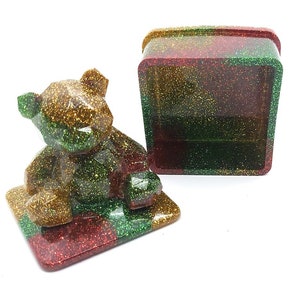 Könnte beinhalten: Eine glitzernde grüne, goldene und rote Bären-Schmuckschatulle mit passendem Deckel. Die Schachtel ist geöffnet und das Innere ist sichtbar.