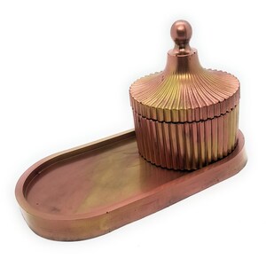 May include: An oval tray and a matching lidded container, both in shades of gold and copper. The container has a fluted design and a rounded top.