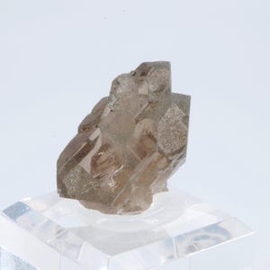 May include: A clear, smoky quartz crystal cluster with multiple facets. The crystal is displayed on a clear acrylic stand.