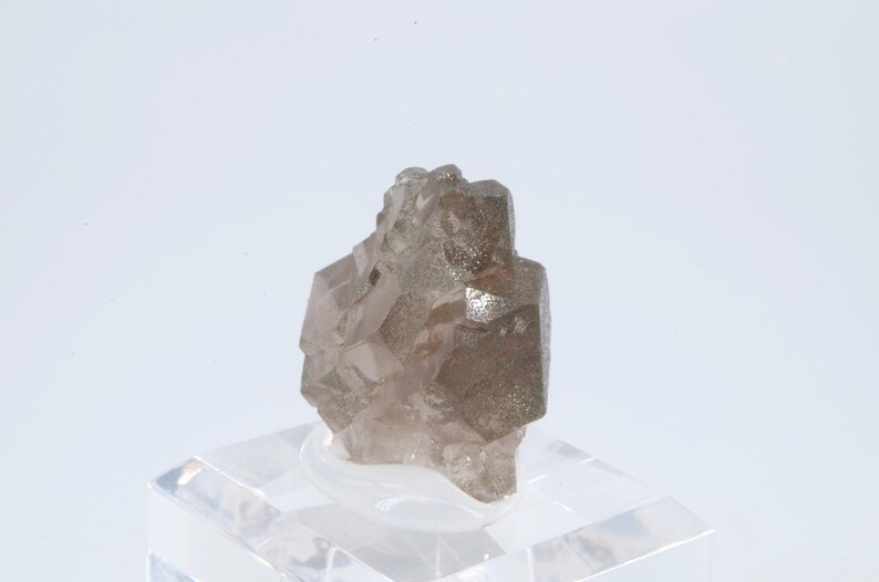 May include: A cluster of smoky quartz crystals with a light brown color. The crystals are intergrown and have a rough, natural surface.