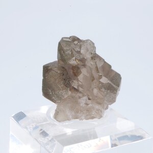 May include: A cluster of smoky quartz crystals with a clear, glassy appearance. The crystals are arranged in a pyramid shape and have a light brown color.