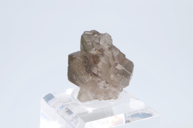 May include: A cluster of smoky quartz crystals with a clear, glassy appearance. The crystals are arranged in a pyramid shape and have a light brown color.