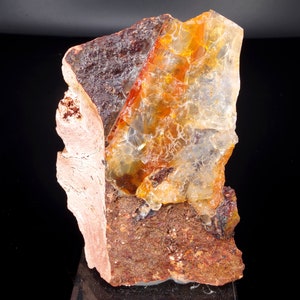 Peut inclure: Un gros morceau de cristal orange et transparent avec une base rocheuse brune.
