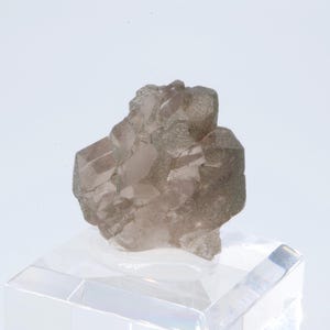 May include: A cluster of smoky quartz crystals with a light pink hue. The crystals are translucent and have a rough, natural texture. The cluster is displayed on a clear acrylic base.