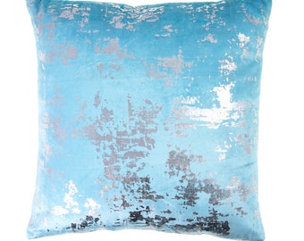 Könnte beinhalten: Ein hellblaues Kissen mit einem silbernen, metallischen, abstrakten Design.