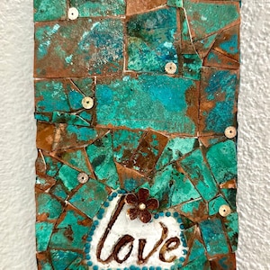 May include: Rectangular mosaic art piece with a turquoise and brown color scheme. The mosaic is made of irregularly shaped pieces. The word "love" is written in cursive on a white heart-shaped element, with a brown flower on top.