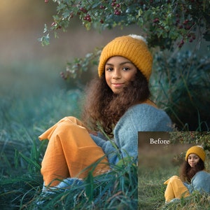 May include: A young person wearing a yellow knit hat and a blue sweater sits in a field of green grass. The person is smiling and looking at the camera. The background is blurred and out of focus.