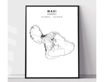 May include: Black framed print featuring a detailed black and white map of Maui, Hawaii. The text "MAUI HAWAII" is centered at the top, with the coordinates 20.7984°N - 156.3319°W below. The map shows roads and geographical features.
