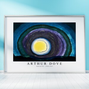 Puede incluir: Una impresión enmarcada de una pintura abstracta de Arthur Dove titulada "Sunrise III". La pintura presenta un gran círculo amarillo rodeado de anillos concéntricos de azul, morado y verde.