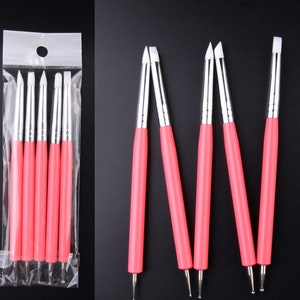 Puede incluir: Conjunto de seis herramientas de arte de uñas de color rosa y blanco con puntas de silicona. Las herramientas están empaquetadas en una bolsa de plástico transparente.