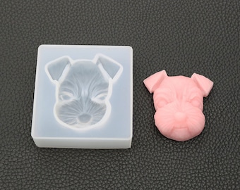 May include: A clear silicone mold shaped like a dog's head, with a pink resin casting of the dog's head next to it.