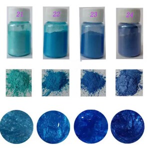 May include: Four small jars of blue and turquoise iridescent pigment powder. The jars are labeled 21, 22, 23, and 24. The powder is shown in three states: in the jar, loose, and as a thick paste.