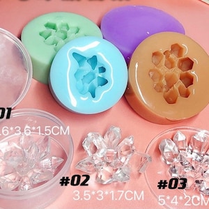Op de afbeelding: Drie siliconen mallen voor het gieten van hars. De mallen zijn in de vorm van een honingraat, een bloem en een kristal. De mallen liggen op een roze oppervlak. De tekst #01 3,6*3,6*1,5CM, #02 3,5*3*1,7CM en #03 5*4*2CM is op het oppervlak gedrukt.