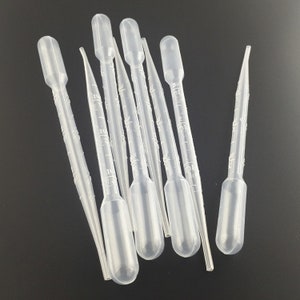 Könnte beinhalten: Ein Satz von zehn klaren Plastik-Tropfern mit Graduierungen. Die Tropfer sind etwa 7,5 cm lang und haben eine bauchige Spitze.