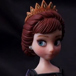 Puede incluir: Una muñeca con el pelo castaño peinado en una trenza, lleva una corona dorada y un vestido negro.