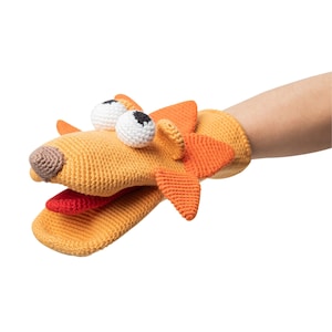 May include: A hand puppet shaped like a dog with orange and yellow crocheted fur. The puppet has large white eyes with black pupils and a red tongue sticking out.
