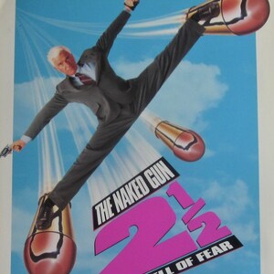 May include: A movie poster for "The Naked Gun 2 1/2: The Smell of Fear" featuring Leslie Nielsen in a suit, flying through the air with his legs spread wide, propelled by large bullets. The title is in pink and white text.