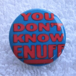 May include: A blue and red button with the text "YOU DON'T KNOW ENUFF" in red letters.