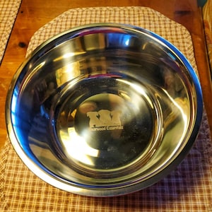 May include: A stainless steel dog bowl with a silver finish. The bowl has a logo engraved on the bottom that says "Bearwood Essentials" with three stylized dogs.