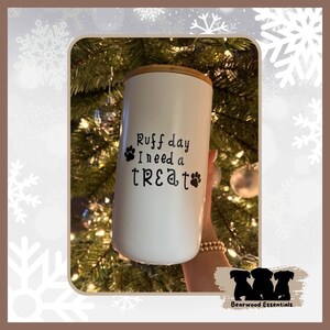 May include: White ceramic treat jar with a bamboo lid. The jar has a black paw print design and the text "Ruff day I need a treat".