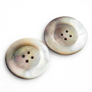 May include: Two round, iridescent, mother-of-pearl buttons with four holes each.