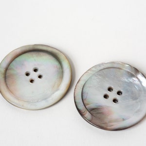 May include: Two large, round, iridescent mother-of-pearl buttons with four holes each.