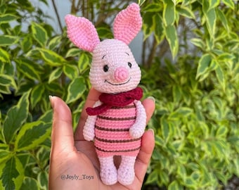 Può includere: Un maialino rosa all'uncinetto con una camicia a righe rosse e bianche e una sciarpa bordeaux. Il maialino ha un viso sorridente con occhi neri e un naso rosa. Il maialino è tenuto in una mano. L'immagine include il testo "@Joyly_Toys".
