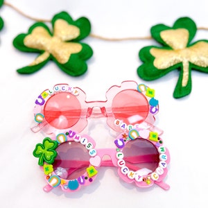 May include: Pink plastic sunglasses with colorful beads spelling out "U Miss U Lucky Charm" and "U Lucky Babe".