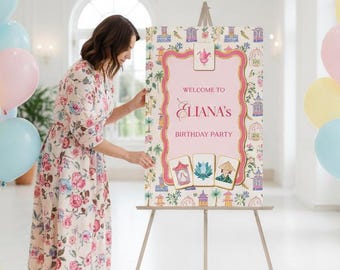 May include: A party sign on an easel with the text "Welcome to Eliana's Birthday Party." The sign is decorated with a pink frame and floral and birdcage illustrations. Pastel balloons in pink, blue, and yellow are arranged around the sign.