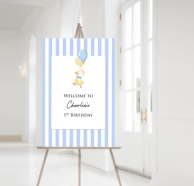 Puede incluir: Un letrero de bienvenida para una fiesta de primer cumplea&ntilde;os. El fondo es de rayas azules y blancas, con un rect&aacute;ngulo blanco en el centro. Muestra una ilustraci&oacute;n de acuarela de un pato amarillo con globos. El texto dice "Welcome to Charlie's 1st Birthday".