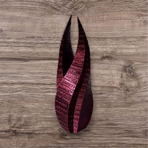 May include: A dark red, 3D printed sculpture of a stylized, abstract, geometric shape. The sculpture is made up of many small, rectangular pieces that are stacked on top of each other. The sculpture is reminiscent of a stylized, abstract, geometric shape.
